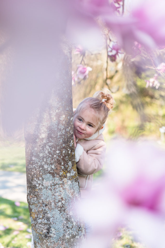 Petite fille jouant derrière un magnolia