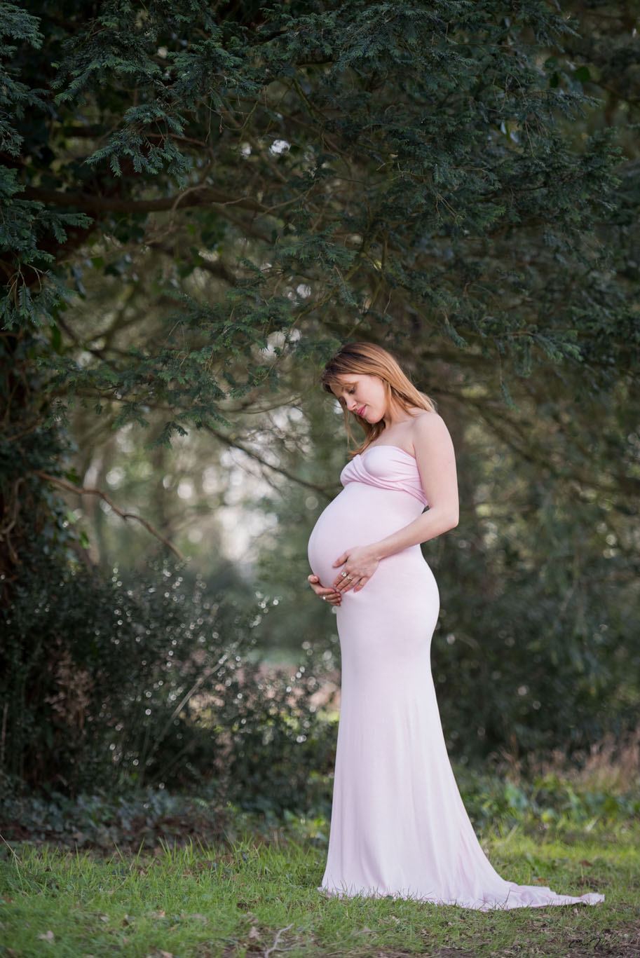 Jeune femme enceinte avec une robe rose dans un parc
