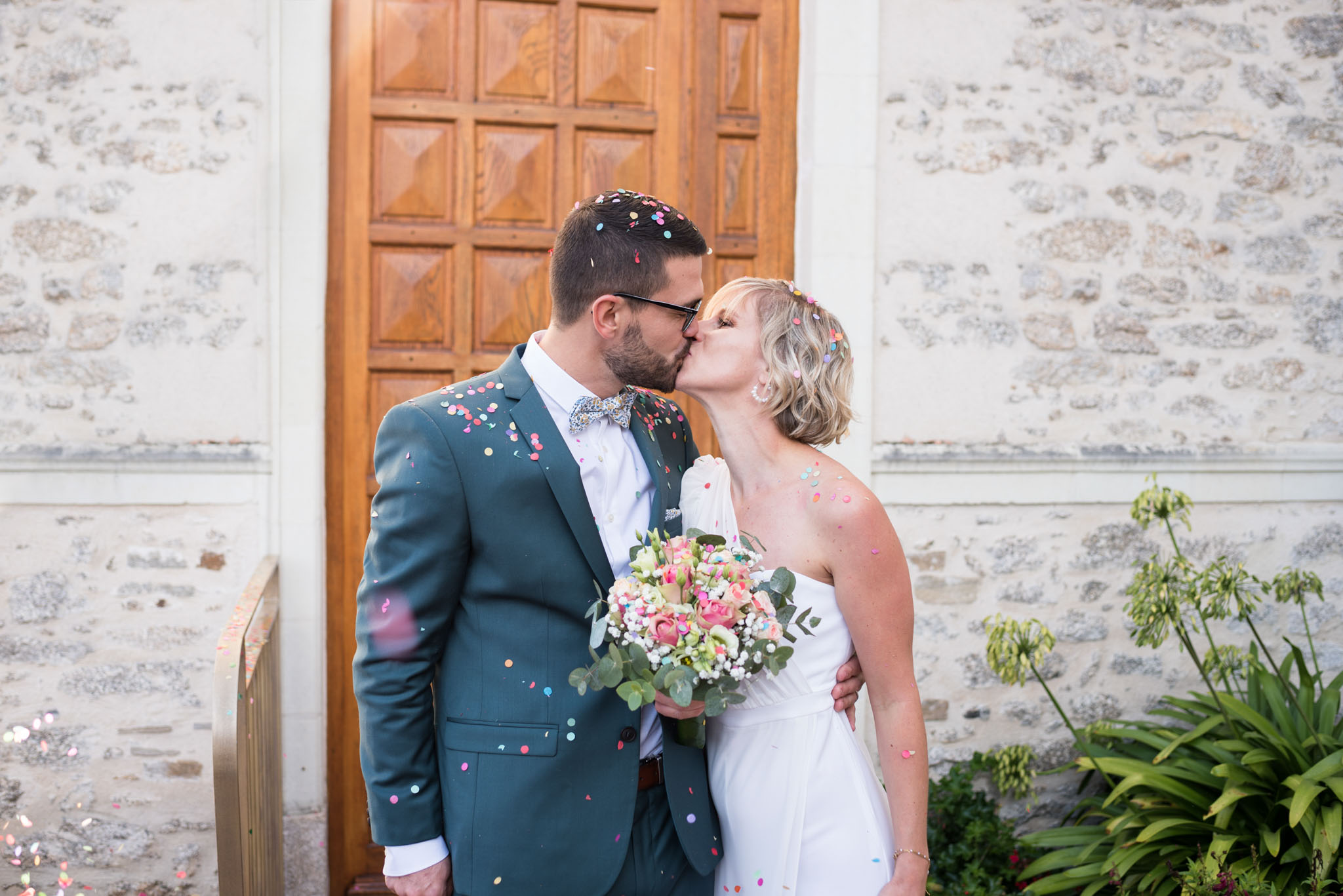 Mariés s'embrassant à l'issue de leur cérémonie civile, couverts de cotillons