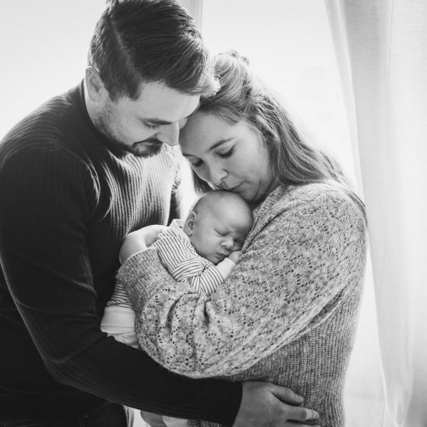 Parents se prenant dans les bras avec leur bébé, photo en noir et blanc