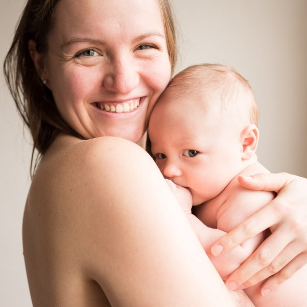 Maman souriant et portant son bébé en peau à peau