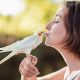 Jeune femme faisant un bisou à son oiseau posé sur sa main